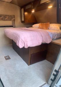 ein Bett mit einer rosa Bettdecke in einem kleinen Zimmer in der Unterkunft Cozy camper in Dunnellon