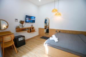 a bedroom with a bed and a desk and a television at Trăng Non Homestay in Phan Thiet