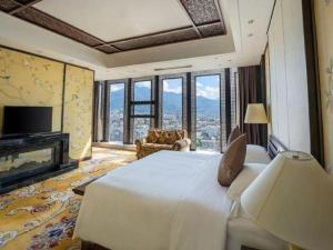 ein Schlafzimmer mit einem großen weißen Bett und einem Fernseher in der Unterkunft Balan International Hotel in Dujiangyan