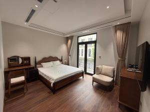 a bedroom with a bed and a tv and a chair at MoonLight Homestay in Hòa Bình