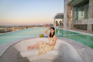 a woman sitting on the edge of a swimming pool at Marquis Hotel in Ban Bang Toei (1)