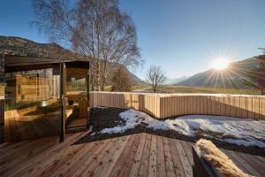 a house with a wooden deck with the sun in the background at fuchs am meer in Mitterhofen