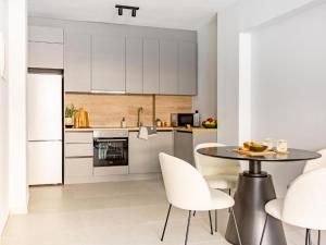 a kitchen with white cabinets and a table and chairs at Ptolemeon 20, Apts & Studios Thessaloniki Center in Thessaloniki