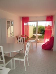 a living room with a table and chairs and a window at Le serpent de mer in Le Grau-du-Roi