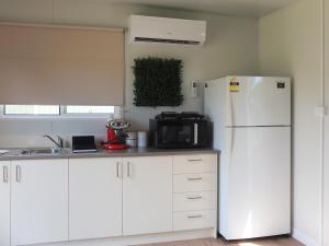 a kitchen with white cabinets and a white refrigerator at Little Birdy in Tawonga
