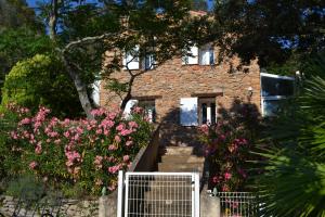 une maison en briques avec des fleurs roses devant elle dans l'établissement Tivoli en Provence, à Cotignac