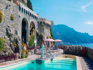 a swimming pool next to a stone building with a lake at Villa Scarpariello Relais in Ravello