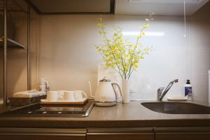 eine Küchentheke mit Spüle und einer Vase mit Blumen in der Unterkunft DL Shinsaibashi in Osaka