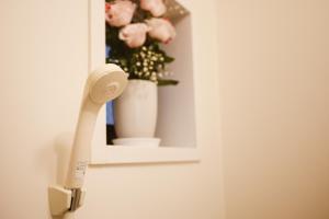 Ein Telefon hängt an der Wand neben einer Vase mit Blumen. in der Unterkunft DL Shinsaibashi in Osaka