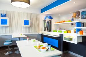 eine Küche mit blauen und weißen Arbeitsflächen und Tischen in der Unterkunft ibis budget Sucy en Brie in Sucy-en-Brie