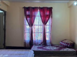a bedroom with a window with red curtains at Aashray kunj homestay in Jāmb +4 photos