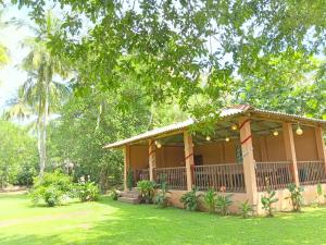 een huis met een veranda in een tuin bij Canal Side Safari Resort in Udawalawe