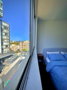 een slaapkamer met een bed en een groot raam bij Cozy Studio near Sydney Hyde Park with Rooftop Pool & FREE Parking in Sydney
