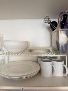 een plank met borden en kopjes in een keuken bij Cozy Studio near Sydney Hyde Park with Rooftop Pool & FREE Parking in Sydney