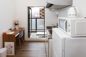 eine kleine Küche mit einem weißen Kühlschrank und einem Tisch in der Unterkunft DL Shinsaibashi in Osaka