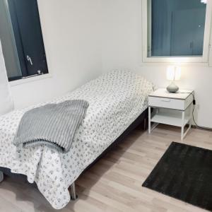 una camera bianca con letto e comodino di Puisto mökki a Rauma