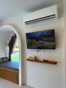 een slaapkamer met een bed en een tv aan de muur bij Hidden Haven Resort Koh Lanta in Ko Bu Bu
