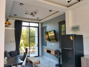 - un salon avec un réfrigérateur et une table dans l'établissement กัสเกรซ โฮมสเตย์, à Pak Chong