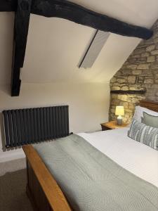 een slaapkamer met een bed en een stenen muur bij Priory Weavers Cottage in Burford