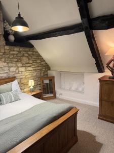 een slaapkamer met een bed en een stenen muur bij Priory Weavers Cottage in Burford
