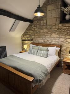 een slaapkamer met een groot bed en een stenen muur bij Priory Weavers Cottage in Burford +31 foto's