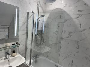 a bathroom with a shower and a sink at Priory Weavers Cottage in Burford