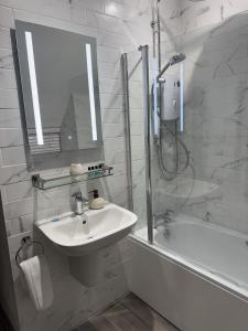 a white bathroom with a sink and a shower at Priory Weavers Cottage in Burford