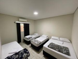 een kamer met drie bedden en een raam bij Casa de alto padrão in Aparecida
