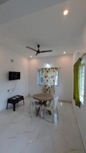 a living room with a table and chairs and a ceiling fan at Dream stay villaa in Pondicherry