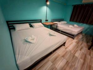 two beds with hats on top of them in a room at Dee-maak Hostel in Thongsala