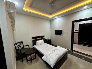een slaapkamer met een bed, een tafel en een stoel bij Osma Living Apartment Peshawar in Peshawar