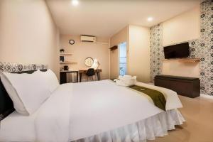 a bedroom with a large white bed and a desk at The Loom Rangsit in Ban Lam Phak Kut