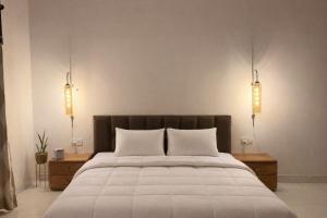 FīrozābādThe RB's Farm的卧室配有一张带两个灯的大白色床