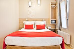 sypialnia z dużym łóżkiem z 2 czerwonymi poduszkami w obiekcie Hotel Eiffel Segur w Paryżu