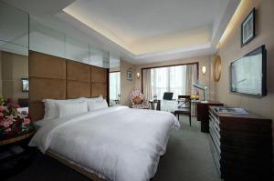 a bedroom with a large white bed and a desk at Shenzhen Hanyong Hotel Fuyong Branch in Fenghuangwei