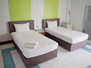 two beds in a room with green and white at Kumkaew Udon in Udon Thani