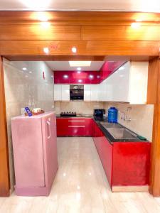 a kitchen with red cabinets and a pink refrigerator at The Boutique Stay in Noida +32 photos