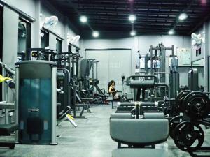 a gym with rows of machines and a woman in the background at The Hub Hotel Surin in Surin