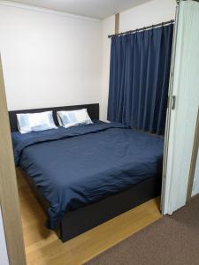 Schlafzimmer mit einem Bett mit blauer Bettwäsche und Kissen in der Unterkunft Nice Access Hotel in Kawasaki