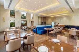 a restaurant with tables and chairs and a blue couch at Raj Leela Heritage Resort By Estherea in Jāmb