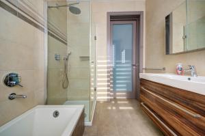 a bathroom with a tub and a sink and a shower at St Julian's 2Br Apartment with Private Jacuzzi in St. Julianʼs +40 photos