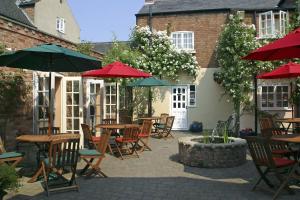 an outdoor patio with tables and chairs with umbrellas at The Cottage Hotel in Nottingham