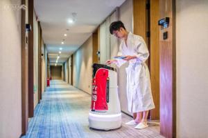 a man standing in a hallway next to a appliance at AURAYA BY SUNING NANJING XUZHUANG in Nanjing