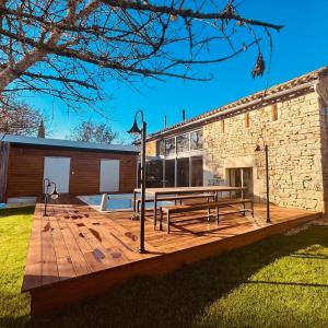 een houten terras met een picknicktafel en een gebouw bij Gîte de Marcenac in Lalbenque