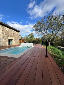 een houten terras met een zwembad naast een gebouw bij Gîte de Marcenac in Lalbenque