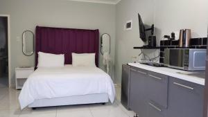 a bedroom with a bed with a purple headboard at Khaya guesthouse in Rustenburg