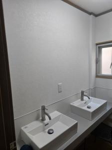 een witte badkamer met 2 wastafels en een spiegel bij Kobe Youth Hostel in Kobe
