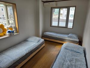 una camera con due letti e uno specchio e due finestre di Kobe Youth Hostel a Kobe