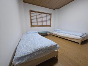 due letti singoli in una stanza con finestra di Kobe Youth Hostel a Kobe Altre 20 foto