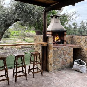 une terrasse en pierre avec une cheminée et deux tabourets dans l'établissement Casa Rural Privada Arenosos, à Pruna
